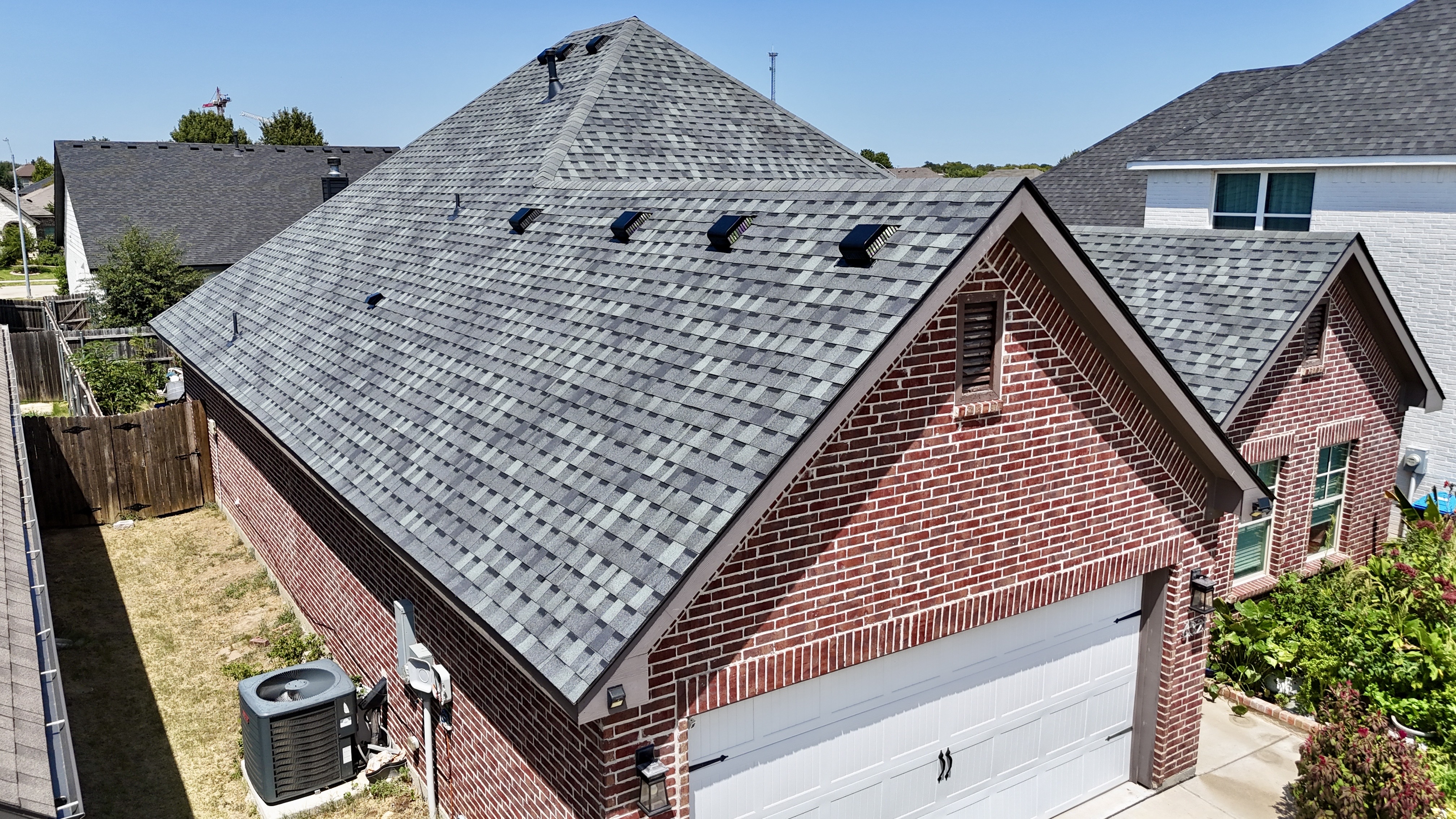 Aerial view of completed gray roof over brick home garage