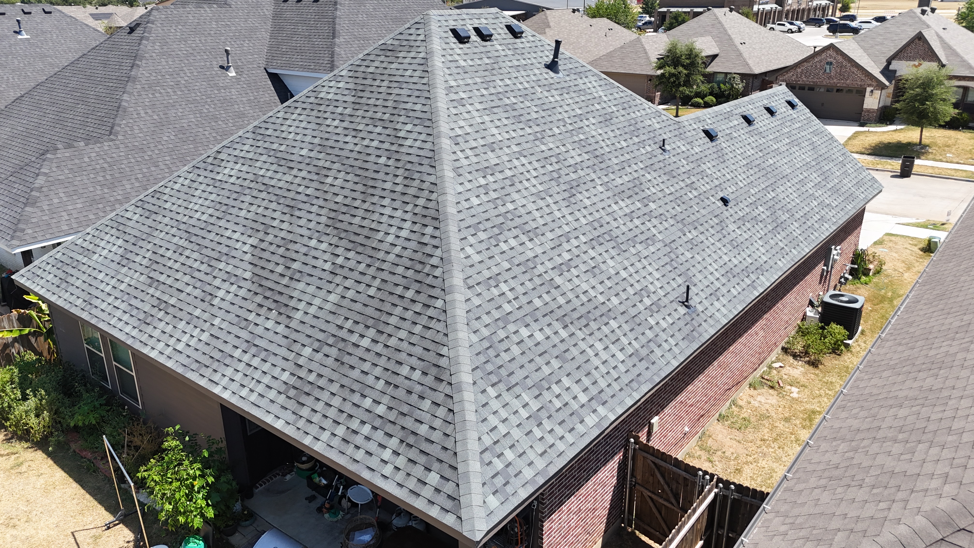 Aerial view of completed gray hip roof with ridge vents