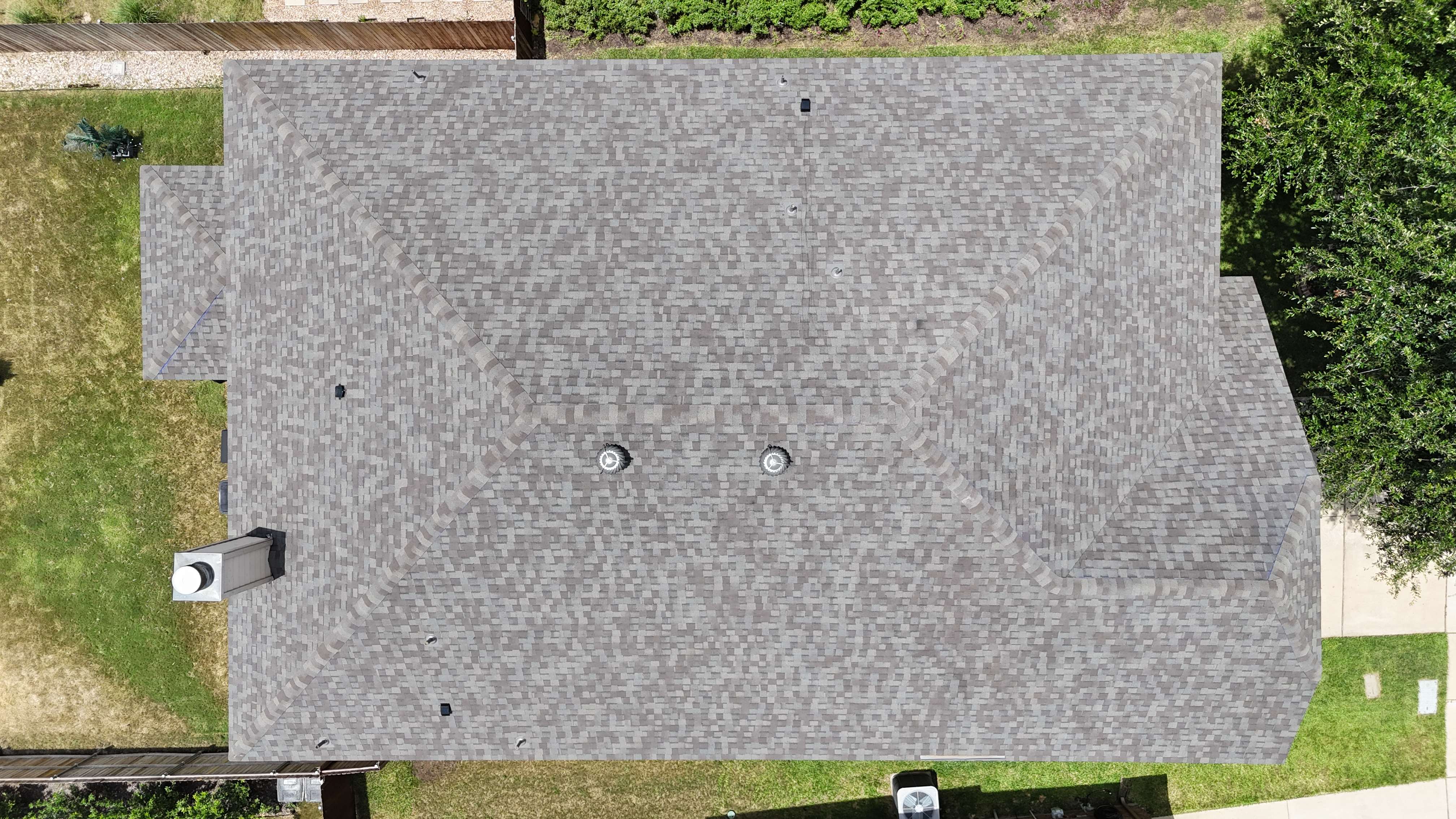 Top-down aerial view of completed brown shingle roof with turbine vents
