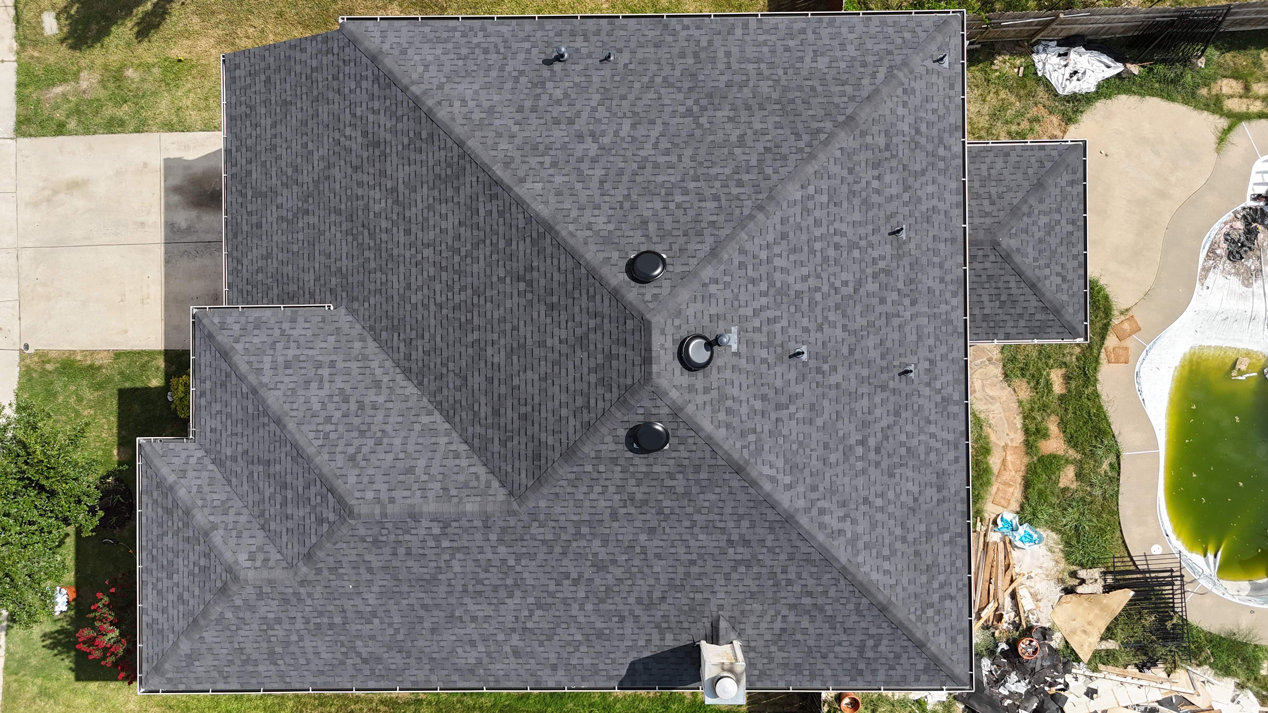 Top-down aerial view of completed charcoal shingle roof with backyard pool