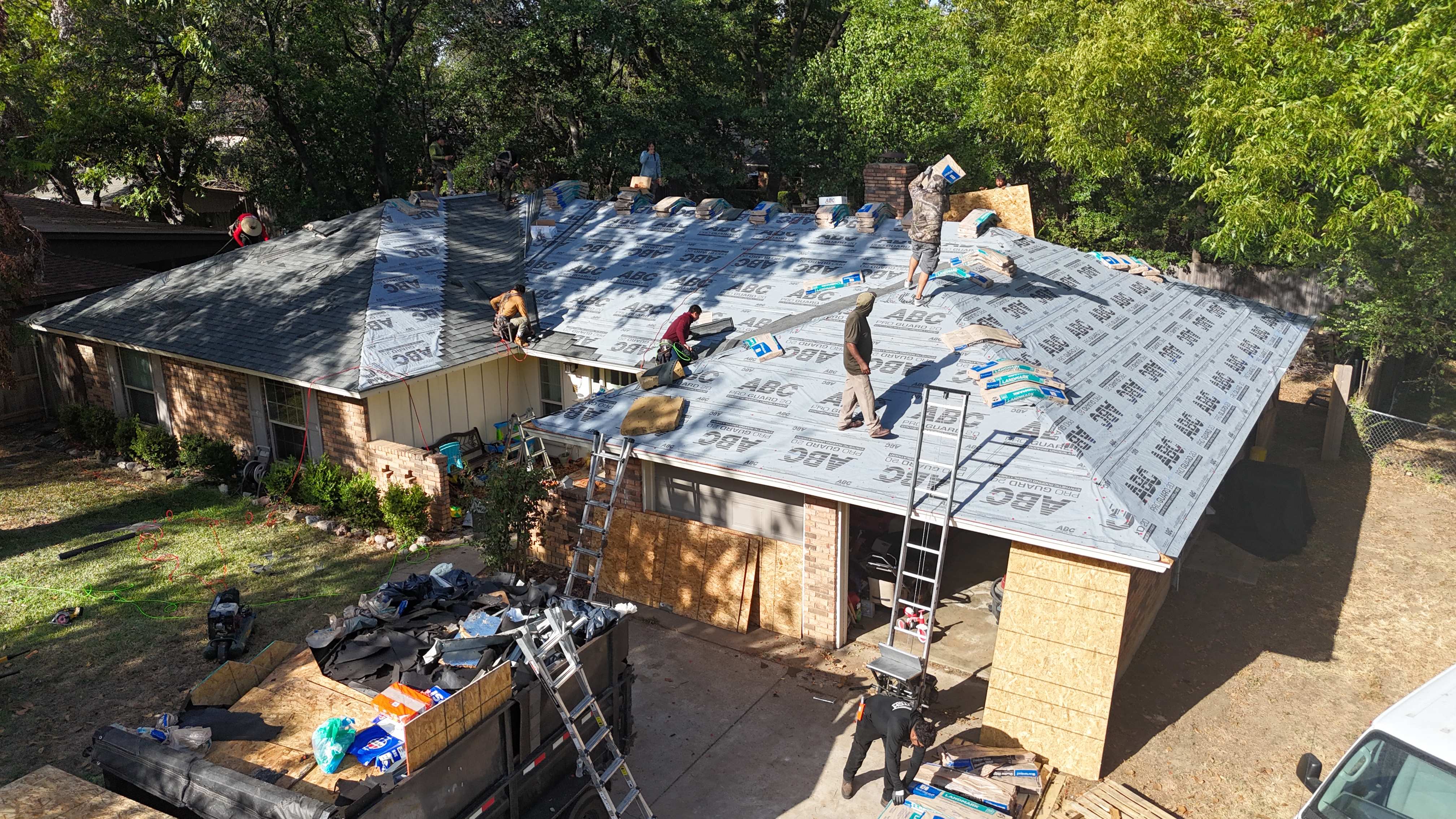 Aerial view of ABC Pro Guard synthetic underlayment with crew loading shingle bundles