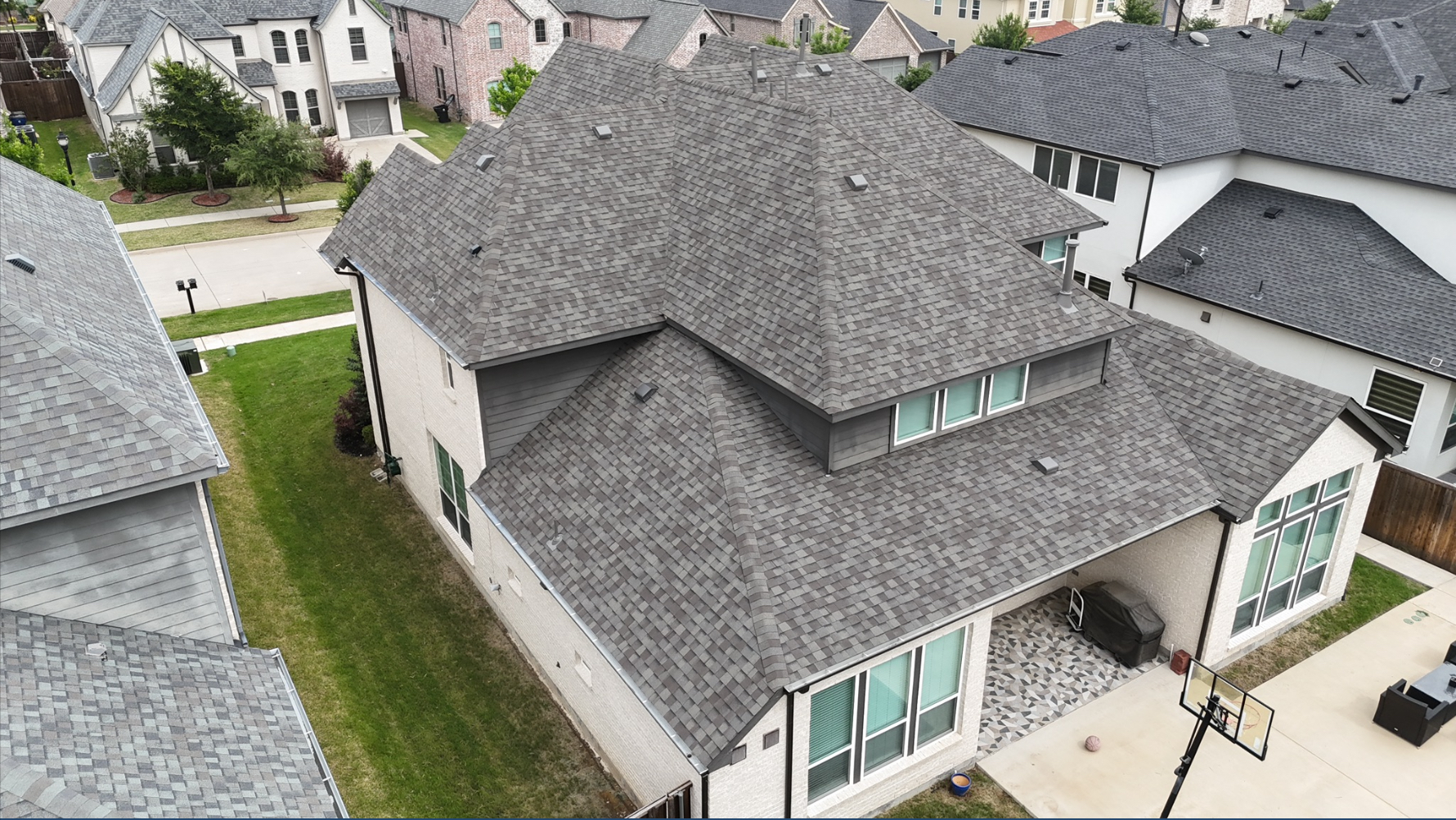 Aerial backyard view of completed gray roof with patio area