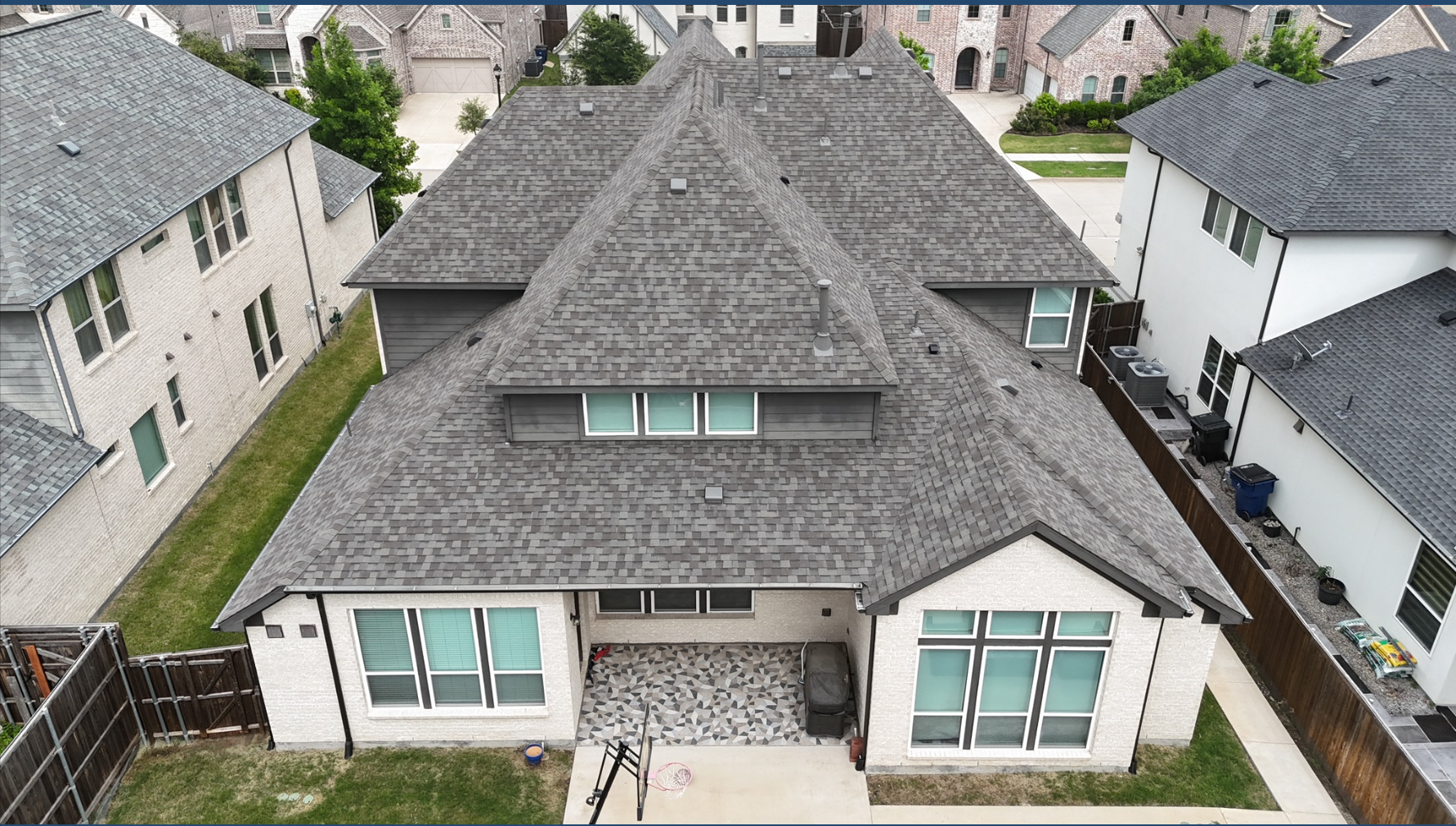 Aerial backyard view of completed gray roof on white painted brick home