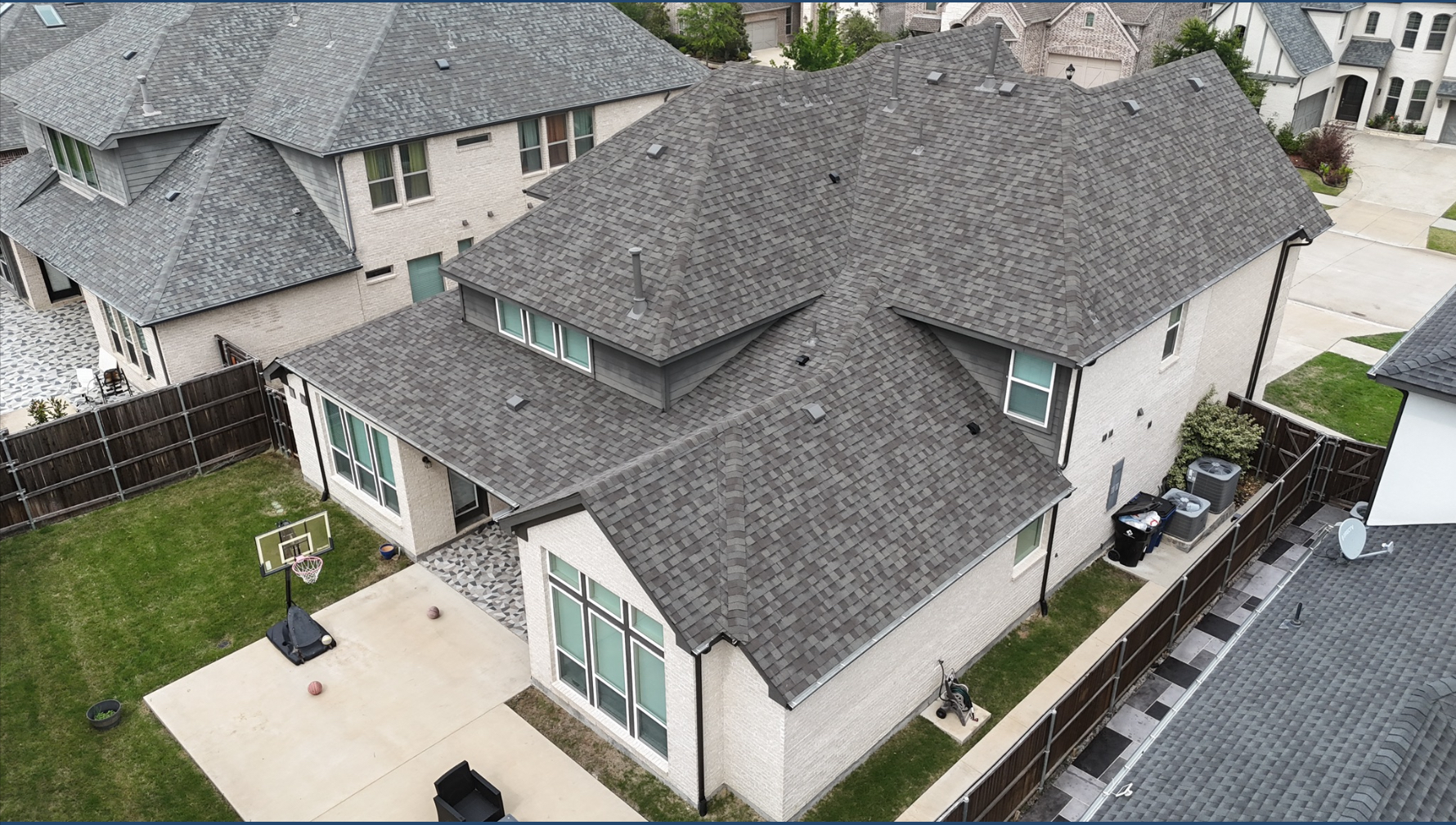 Aerial view of completed gray roof showing full coverage on white brick home