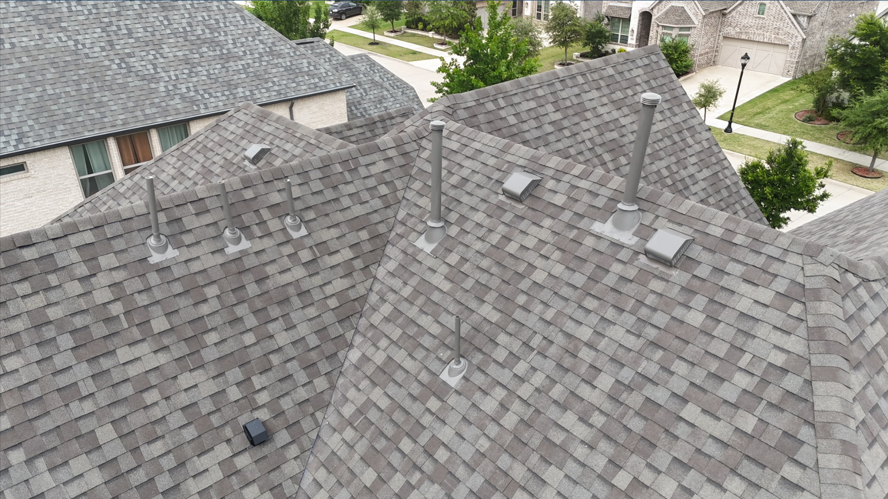 Close-up aerial showing pipe boots and vents on completed gray shingles