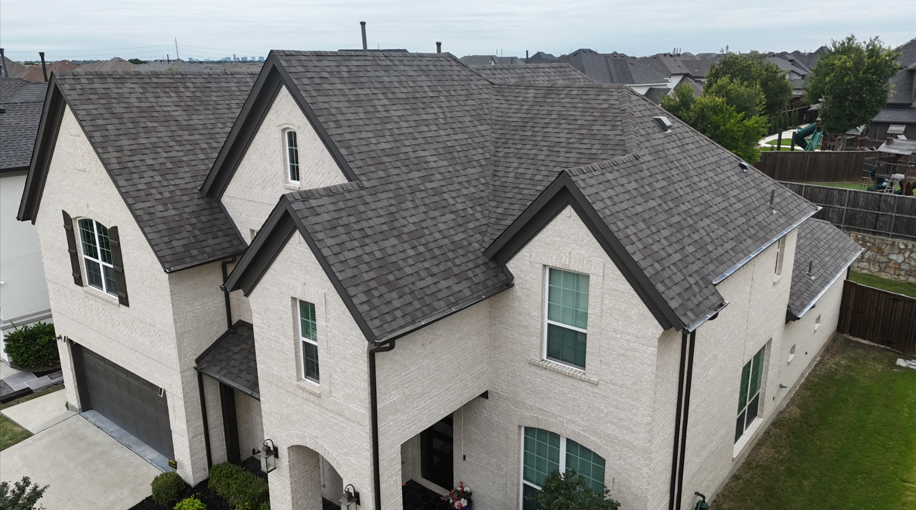 Beautiful completed charcoal roof on white brick home - front view