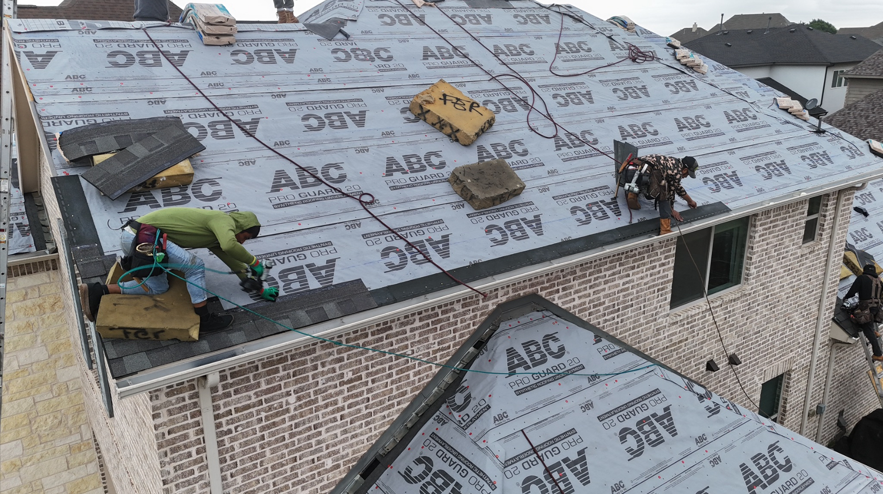 Roofing crew installing shingles on synthetic underlayment