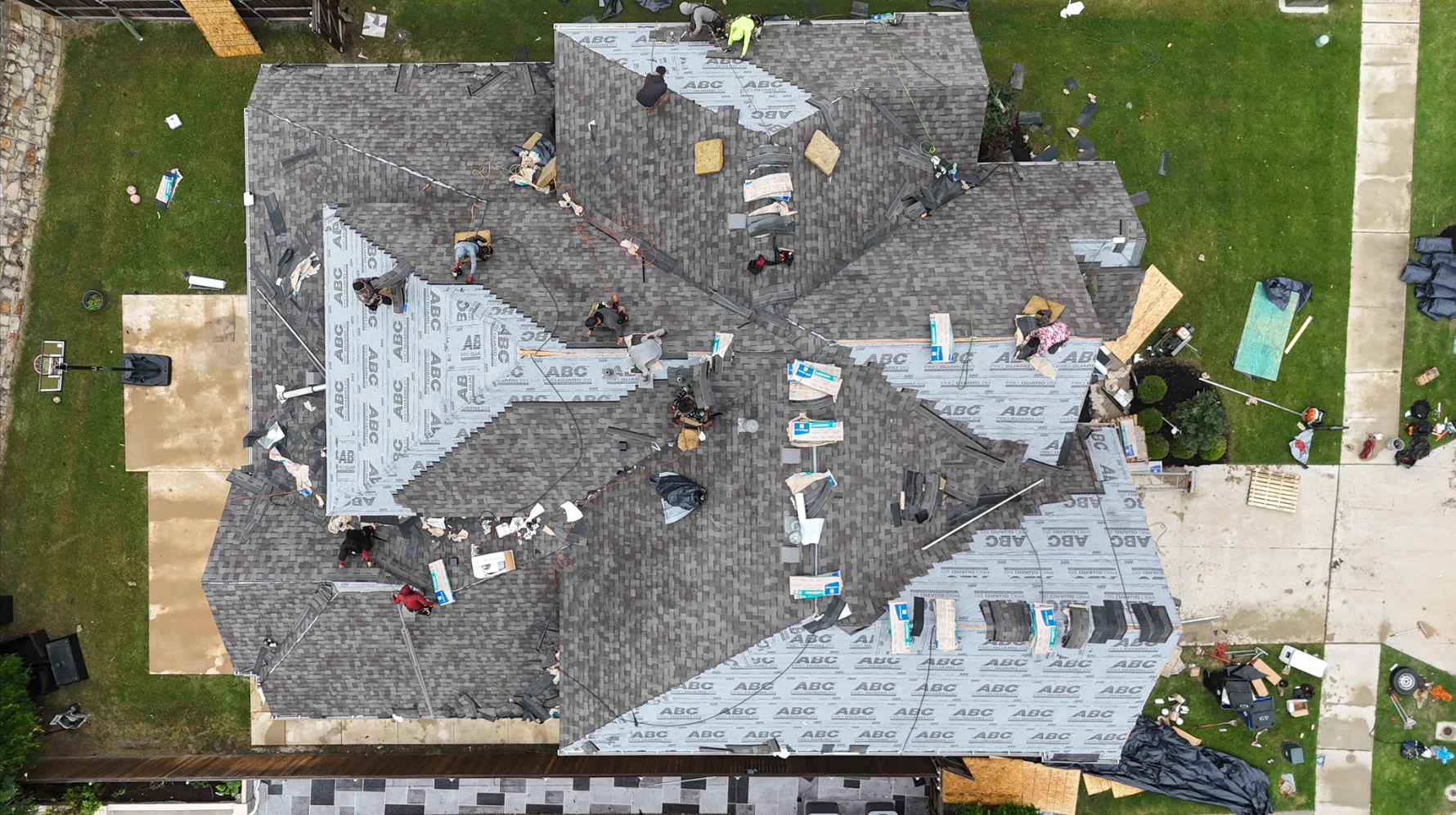 Aerial view of large crew installing shingles on complex roof