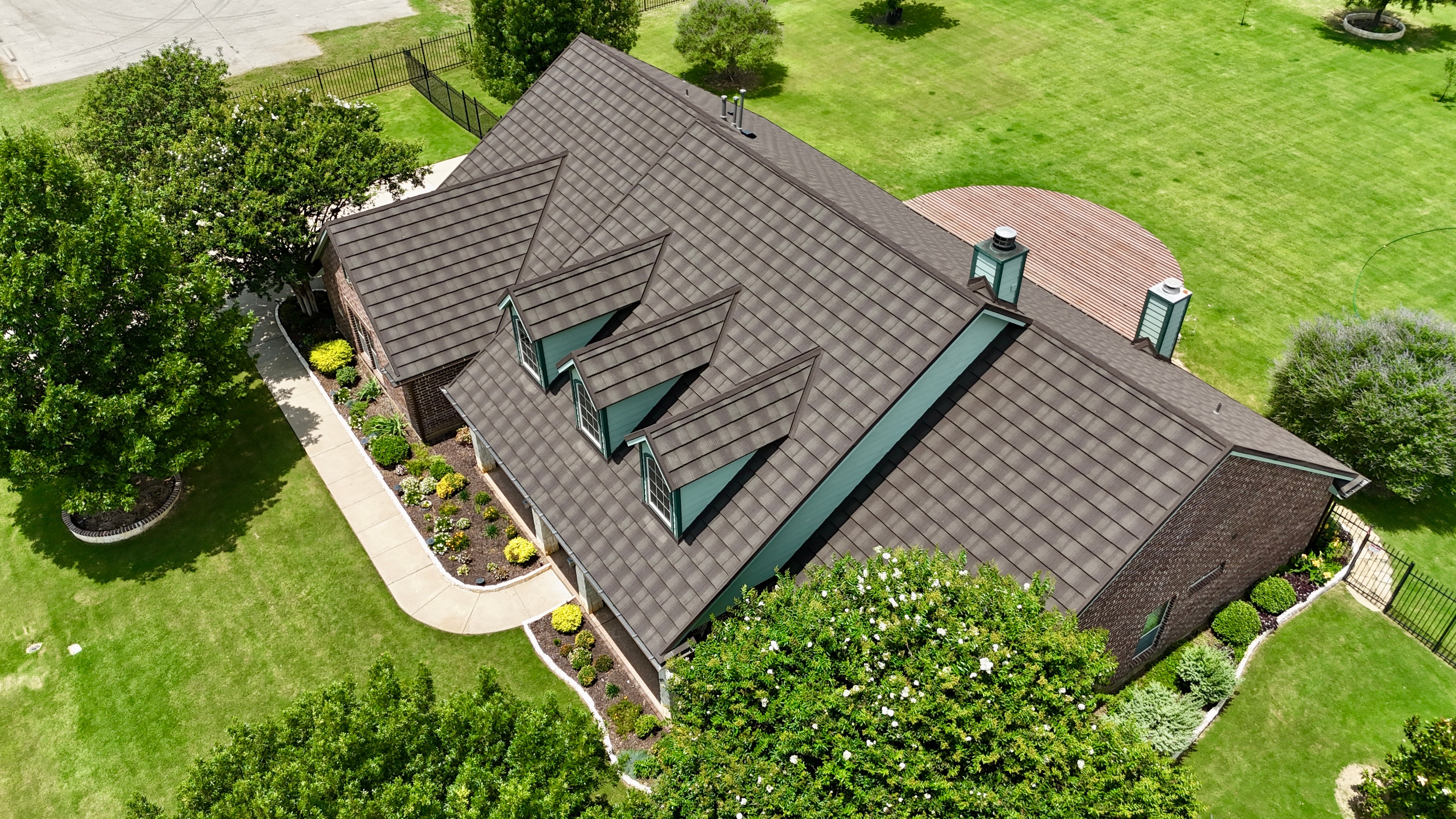 Aerial view of brown stone coated steel roof showing dormers and cupola