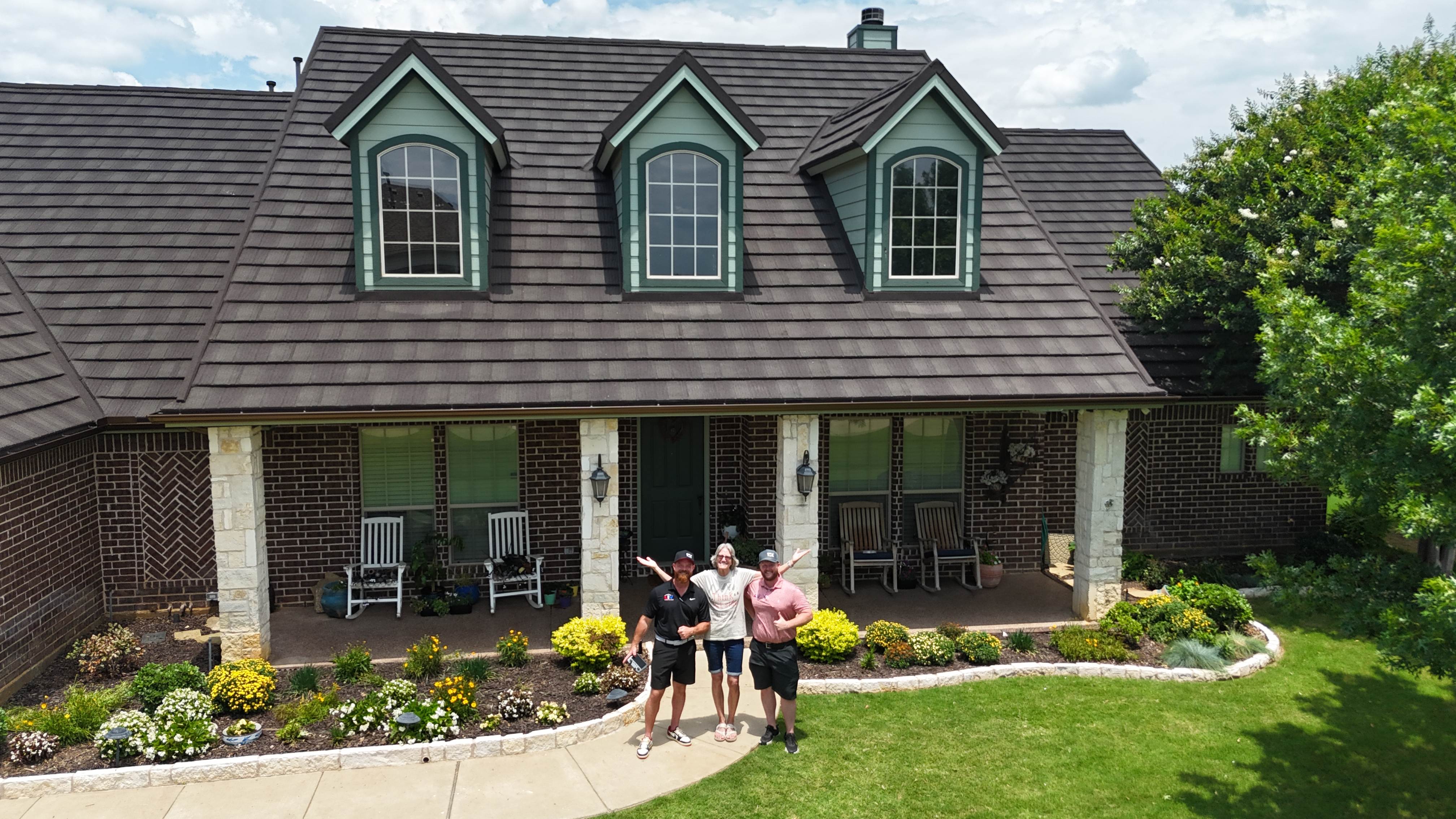 LIV Construction team with happy homeowner in front of completed stone coated steel roof