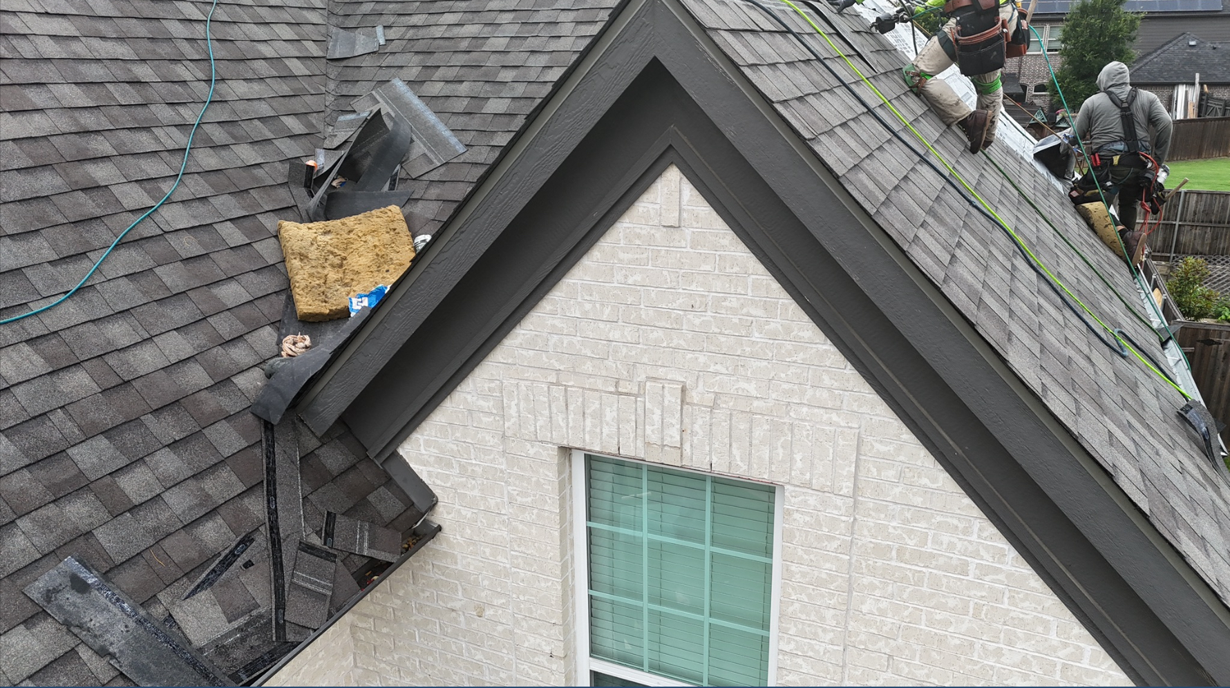 Gray shingles with materials staged on roof during installation