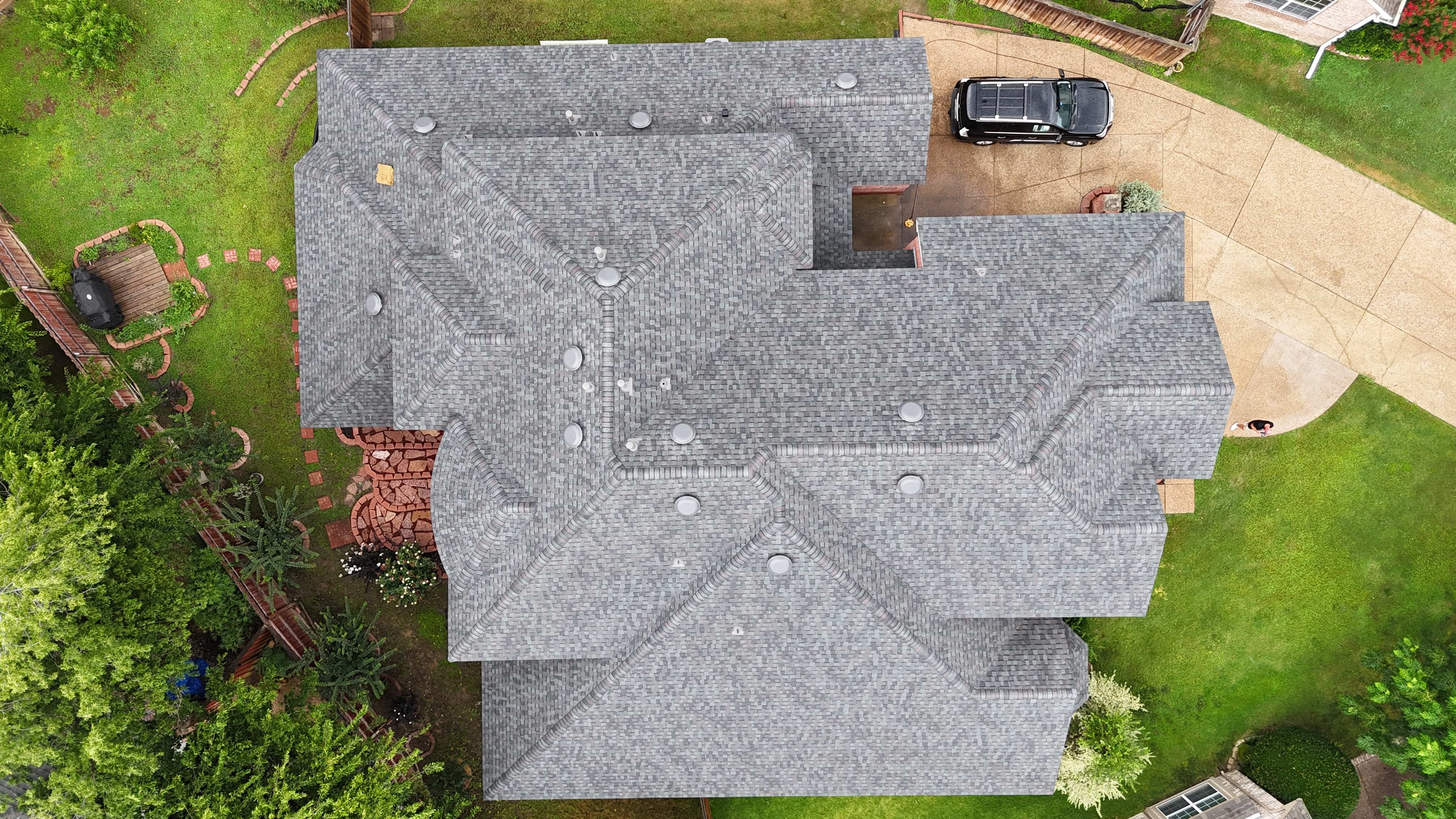 Top-down aerial of completed gray shingle roof on large home
