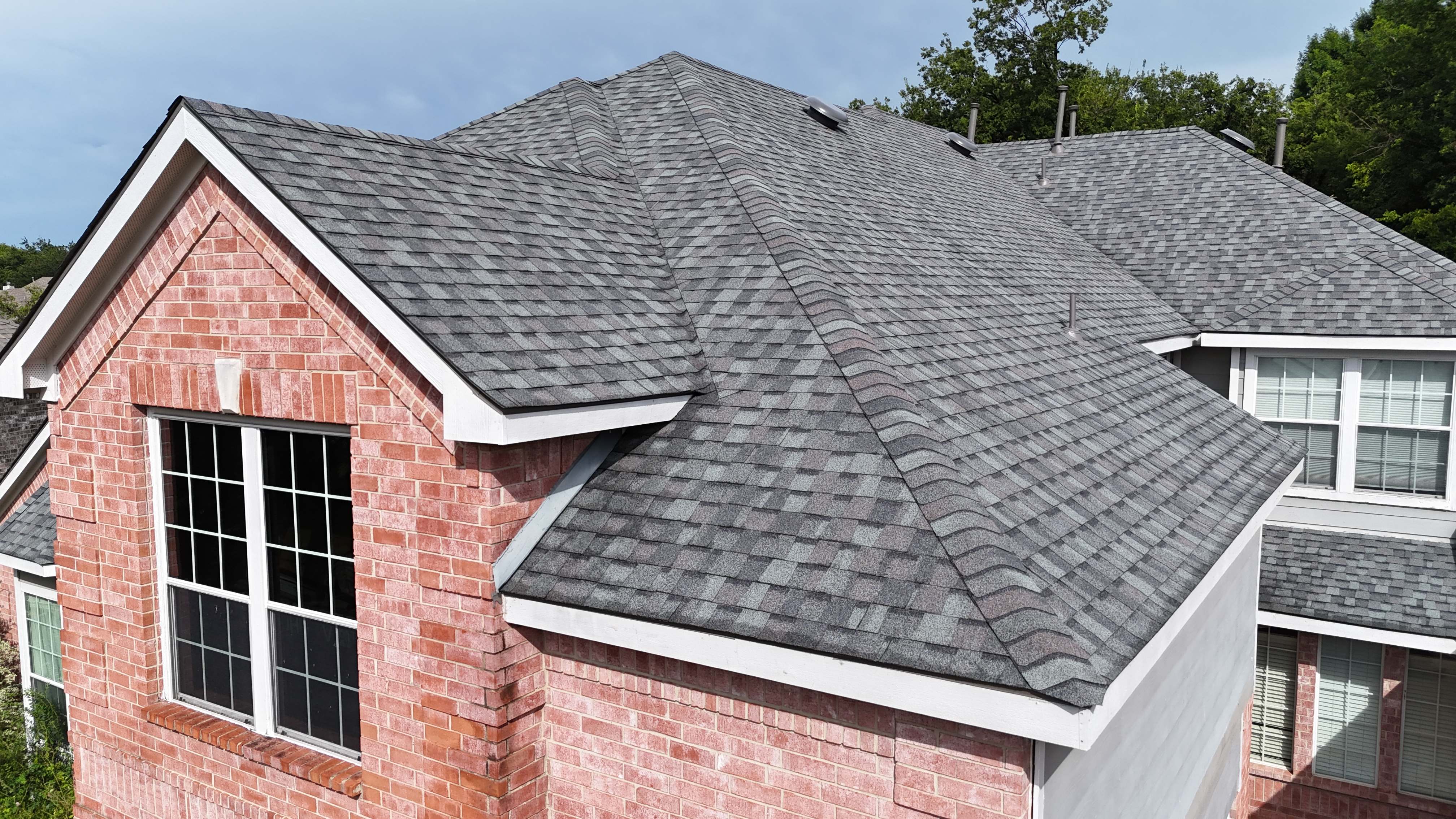 Close-up of new gray architectural shingles on brick home gable