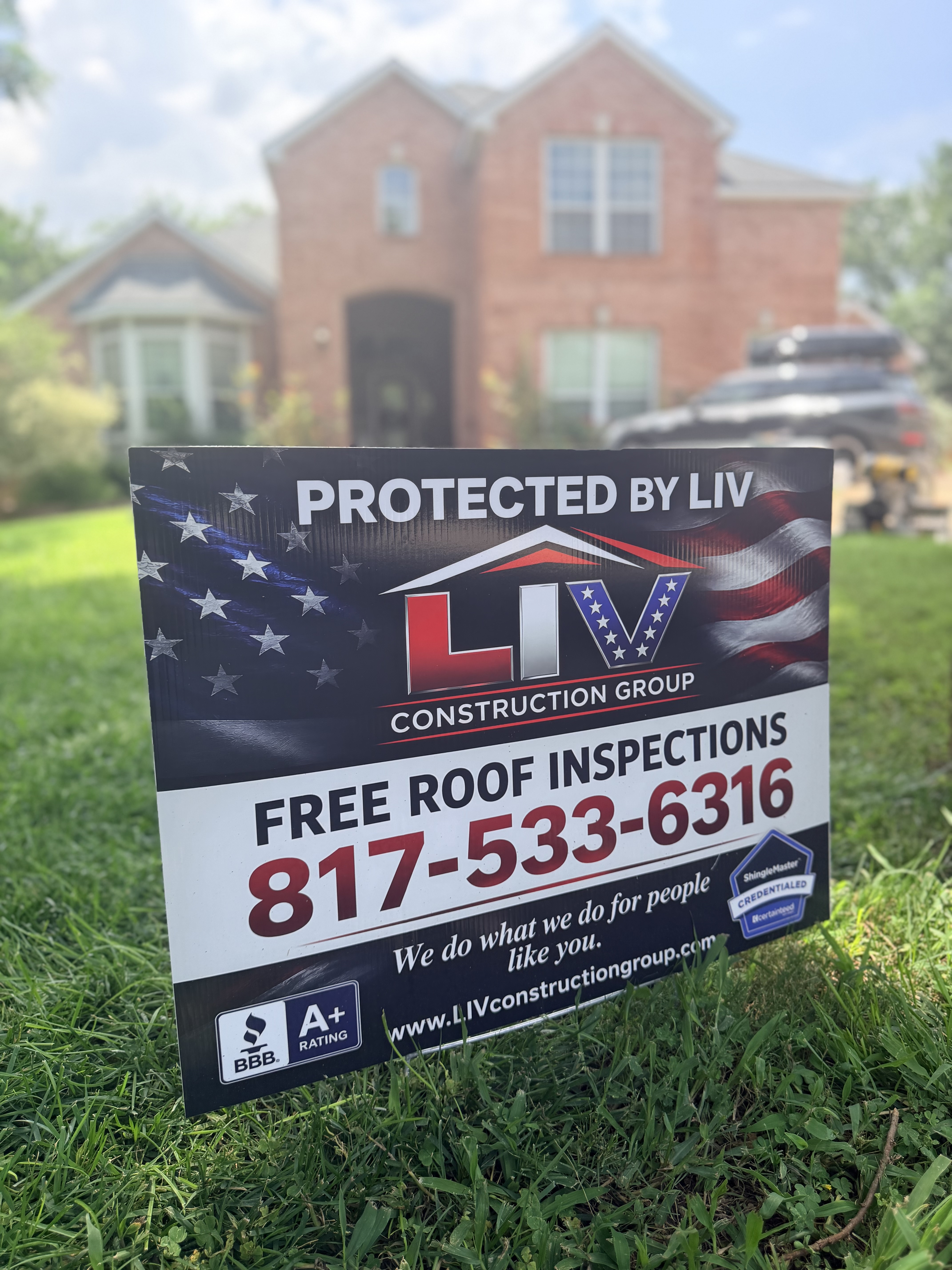 Protected by LIV Construction Group yard sign with free roof inspections and phone number